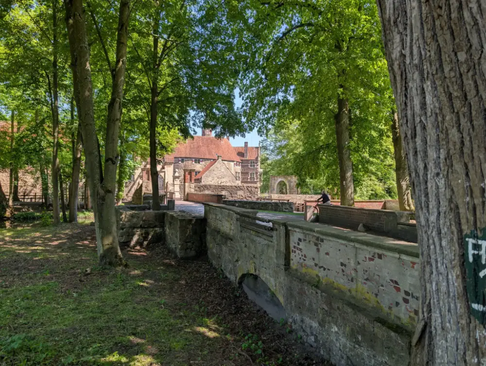 Shaded woodland path with old walls, Burg Vischering castle in Lüdinghausen in the background